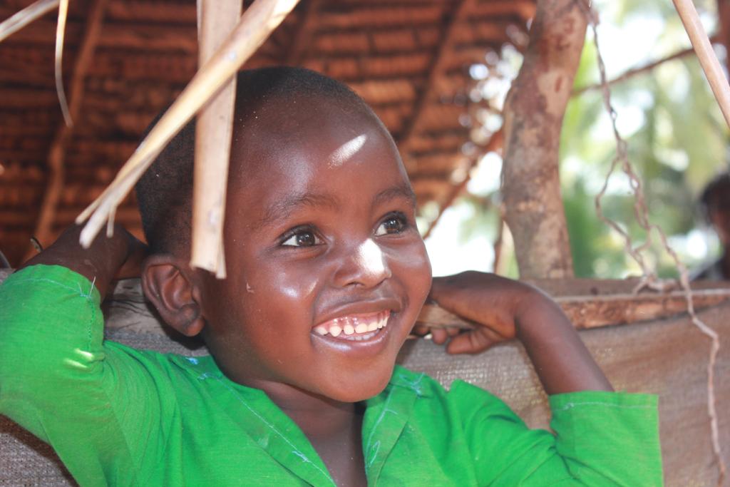Enfant avec une chemise verte qui sourit